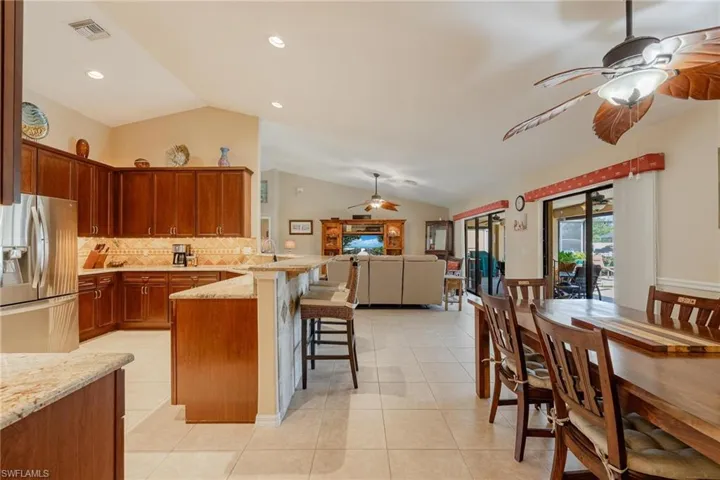 Kitchen featuring ceiling fan, kitchen peninsula, lofted ceiling, a breakfast bar area, and stainless steel fridge with ice dispenser
