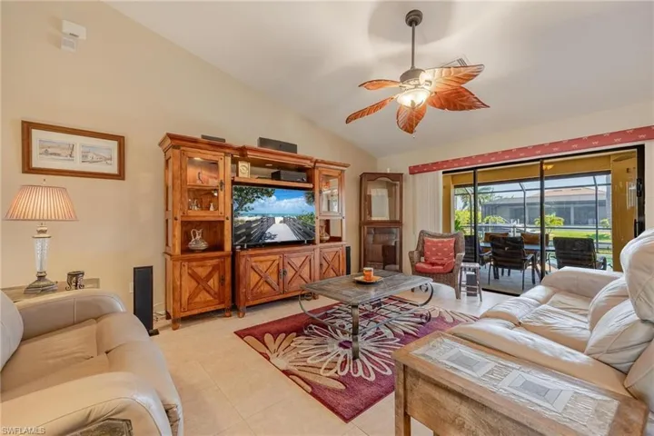 Living room with vaulted ceiling, ceiling fan, and light tile floors