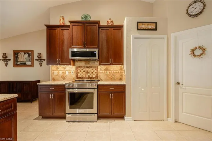 Kitchen with stainless steel appliances, lofted ceiling, and light tile floors