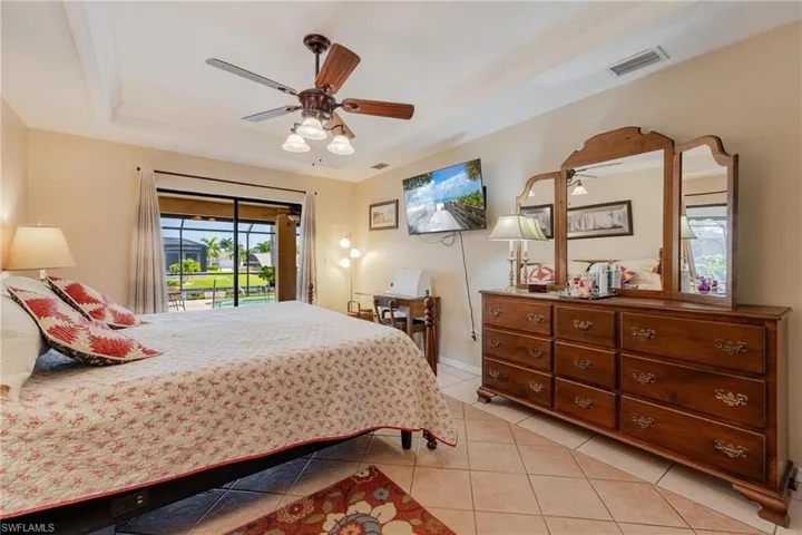 Bedroom featuring a raised ceiling, ceiling fan, access to exterior, and light tile flooring