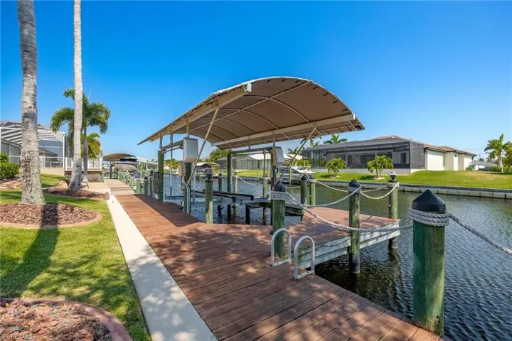 View of dock featuring a lawn, a lanai, and a water view