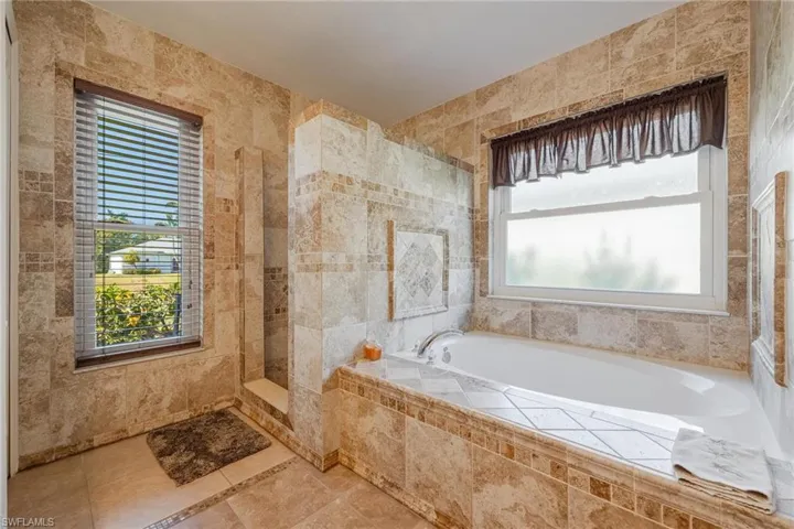 Bathroom with tile walls, tile flooring, and tiled bath