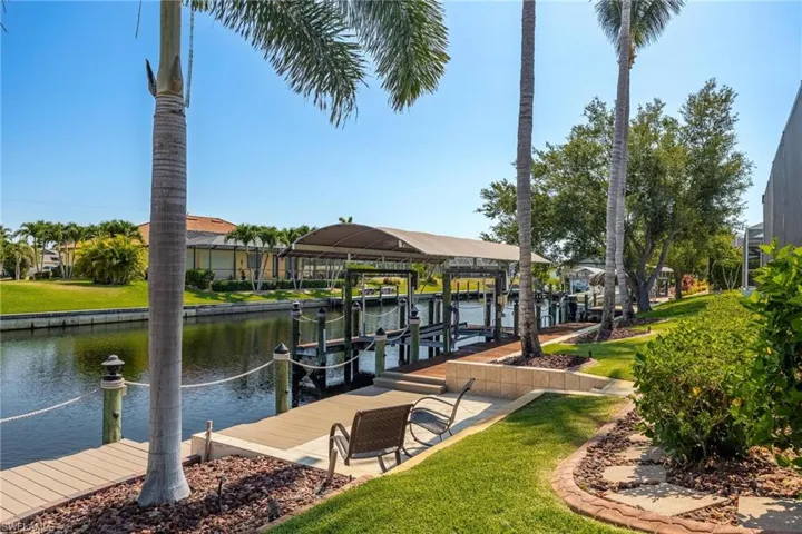 View of dock featuring a lawn and a water view