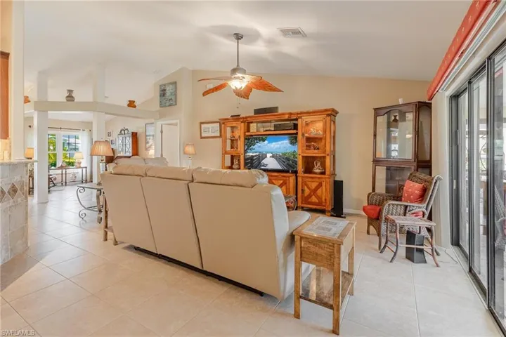 Living room with ceiling fan, light tile floors, and lofted ceiling