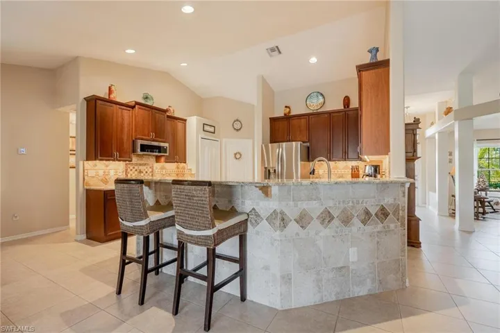 Kitchen featuring appliances with stainless steel finishes, lofted ceiling, and light tile floors