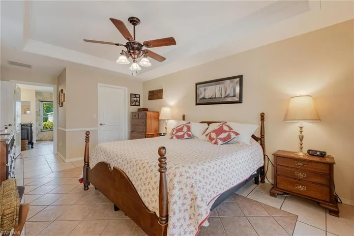 Tiled bedroom featuring ceiling fan and a tray ceiling