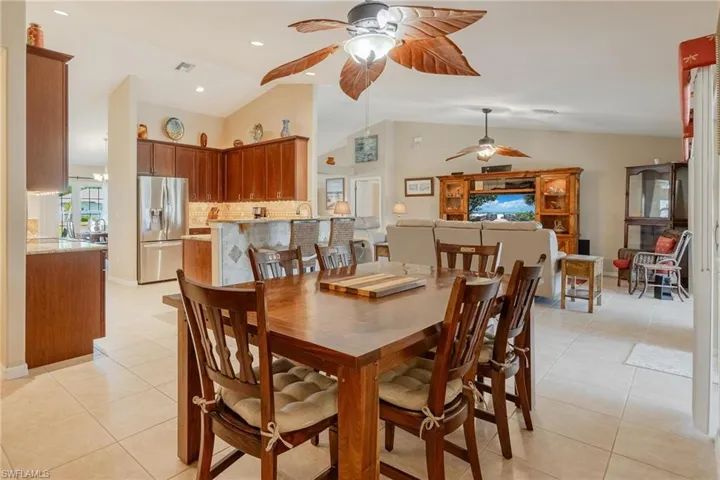 Tiled dining area featuring vaulted ceiling and ceiling fan