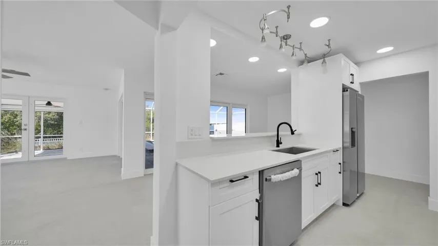 Kitchen featuring concrete floors, white cabinets, stainless steel appliances, light stone counters, and recessed lighting