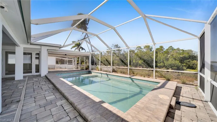 Swimming pool with a patio area, a sunroom, and a lanai
