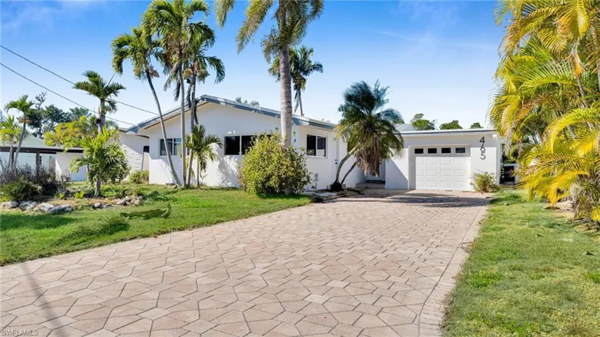 Ranch-style home with a front yard, driveway, stucco siding, and a garage