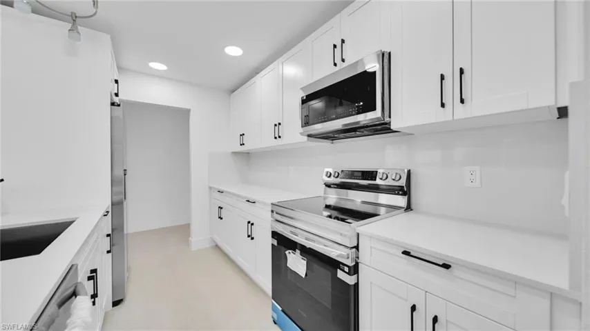Kitchen with stainless steel appliances, white cabinets, recessed lighting, and light stone countertops