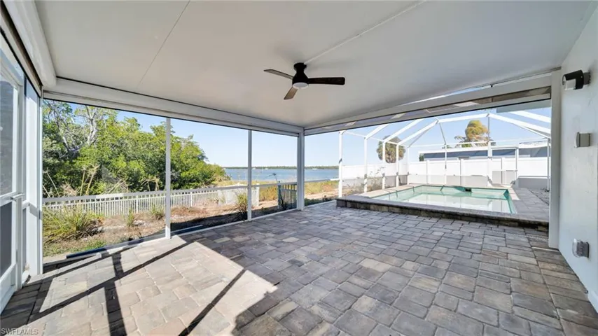Unfurnished sunroom featuring a water view, a ceiling fan, and a patio