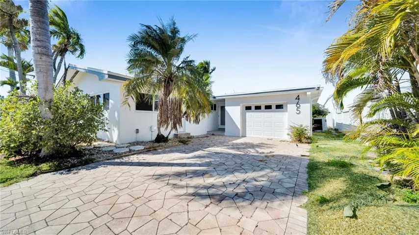View of front of property featuring stucco siding, decorative driveway, and an attached garage