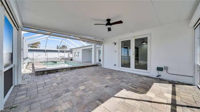 Unfurnished sunroom with ceiling fan, a patio area, a hot tub, and french doors