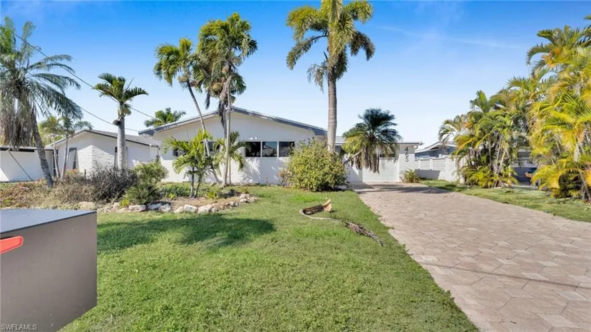 View of front facade with a front lawn, driveway, and stucco siding