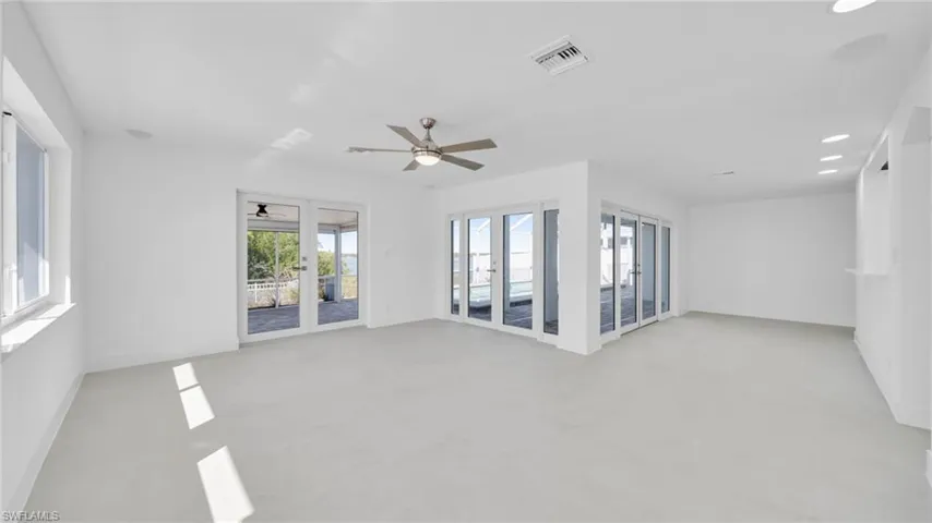 Spare room with french doors, ceiling fan, plenty of natural light, recessed lighting, and concrete floors