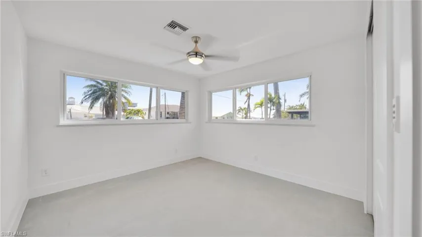 Unfurnished room with finished concrete floors and ceiling fan