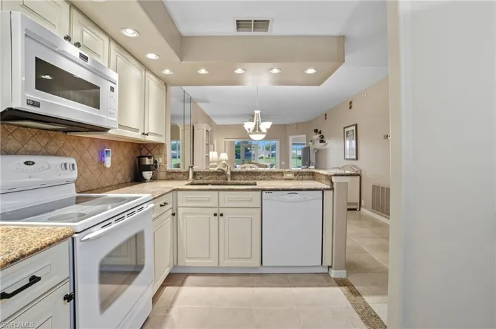 Kitchen with white appliances, recessed lighting, light tile patterned flooring, decorative backsplash, and decorative light fixtures
