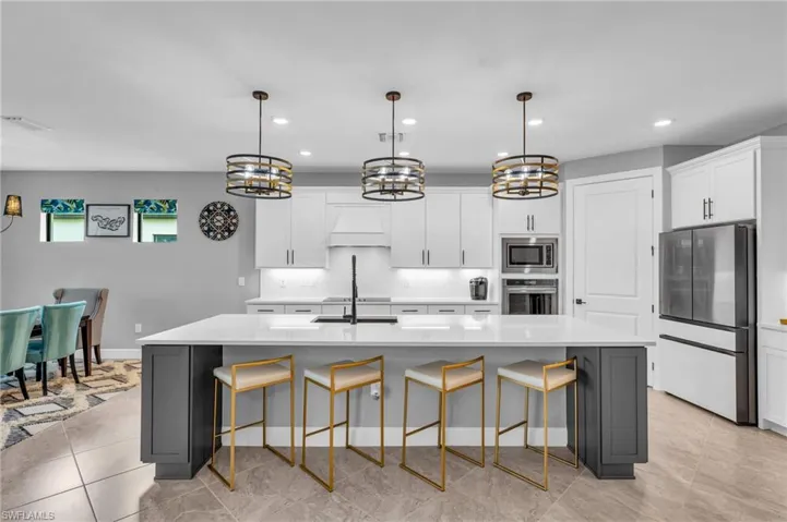 Kitchen featuring a spacious island, appliances with stainless steel finishes, pendant lighting, and white cabinetry