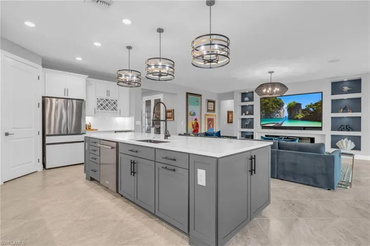 Kitchen featuring an island with grey cabinets, granite sink,  stainless steel appliances and pull out drawers inside cabinets