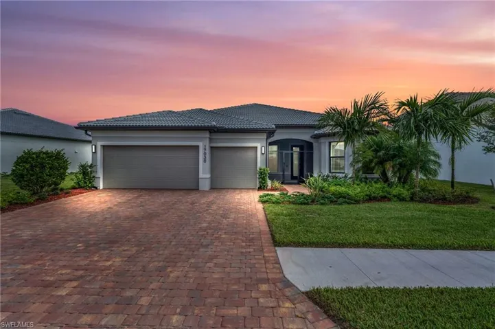 View of front of home at dusk with modern lighting, lush landscape, front screened in porch and 3 car garage