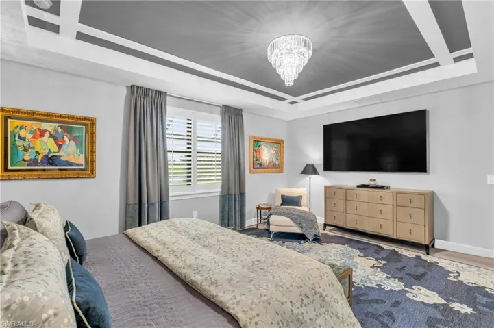 Primary Bedroom Suite featuring a raised ceiling w/accent