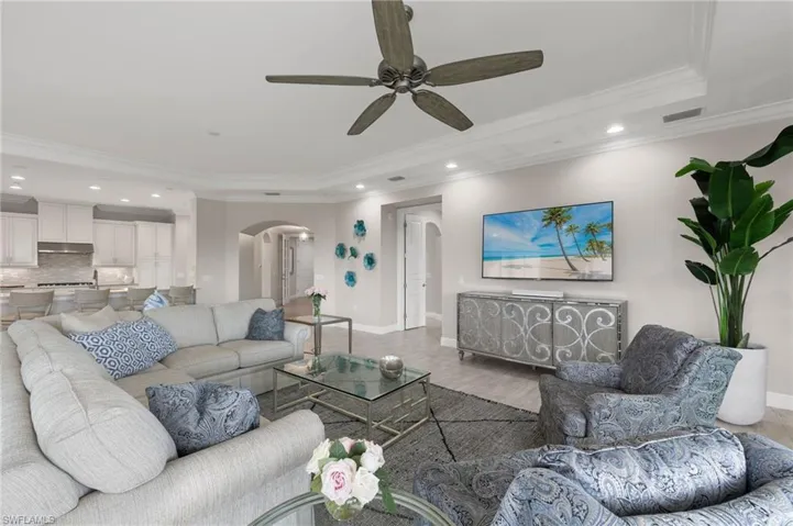 Great Room featuring crown molding, a ceiling fan, a tray ceiling, and arched walkways.