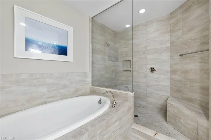 Primary Bathroom featuring a large soaking tub and a walk in shower.