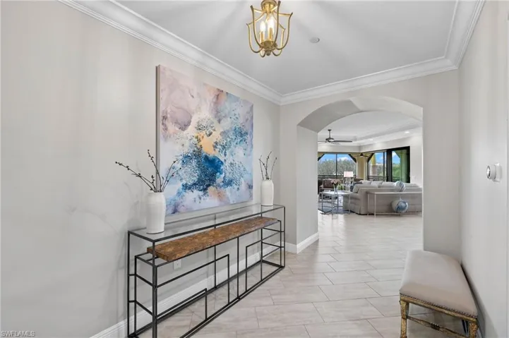 Foyer with arched walkways, crown molding, and a notable chandelier.