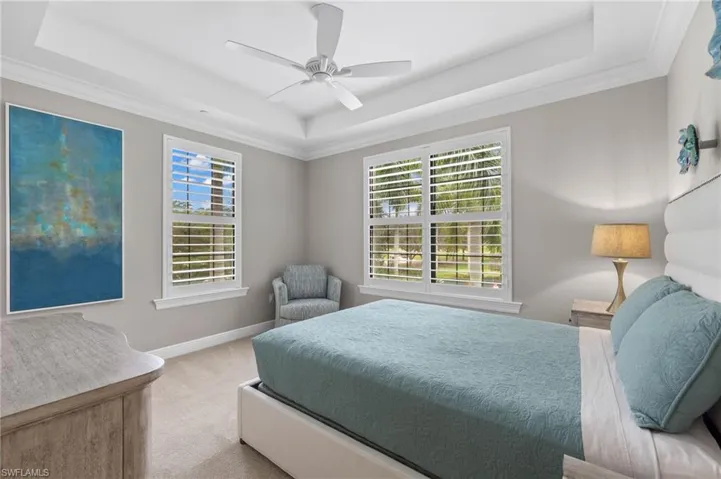 Guest Bedroom 1 with a tray ceiling, and a ceiling fan.