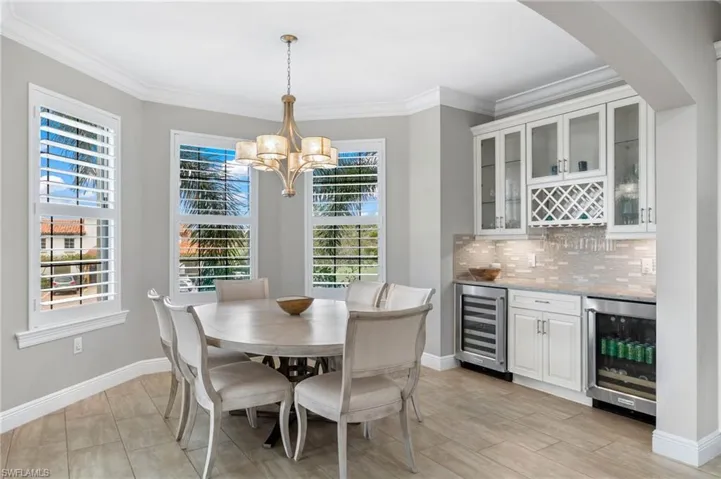Dining space with a decorative chandelier, custom bar area, beverage cooler, and wine cooler.