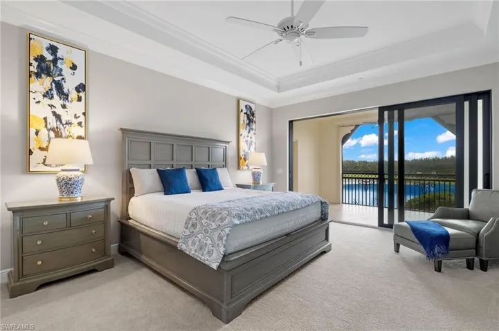 Primary Bedroom with access to exterior, a tray ceiling, and ornamental molding.