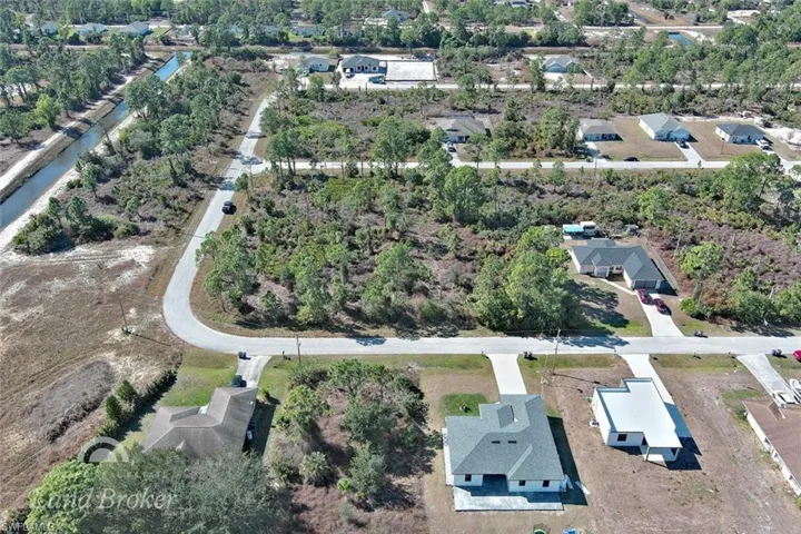 Aerial overview of property's location featuring a tree filled landscape and nearby suburban area