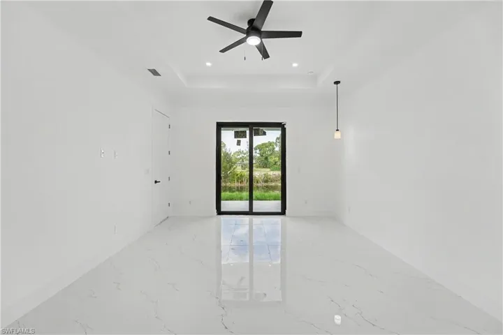 Spacious interior featuring marble-look tile flooring, white walls, and a black ceiling fan
