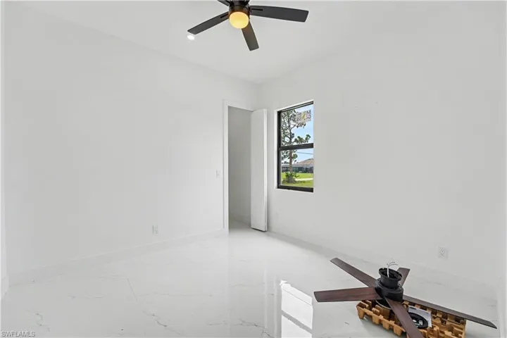 White porcelain tile flooring with subtle veining, white walls, and a black ceiling fan with a central light fixture