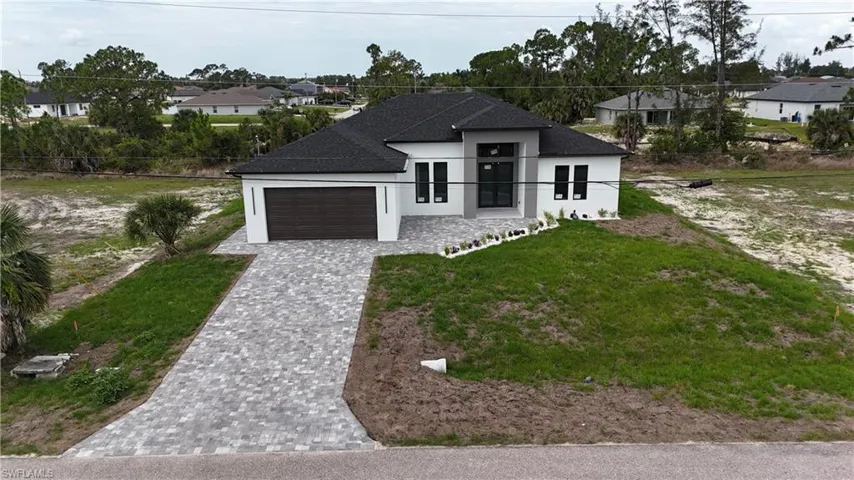 Contemporary single-story residence featuring a dark shingle roof and a paver driveway