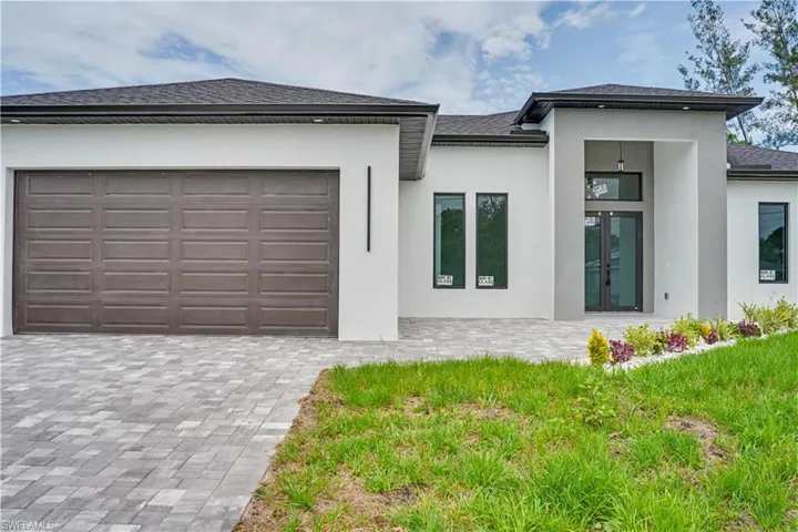 Contemporary stucco exterior featuring a prominent two-car garage with a paneled door