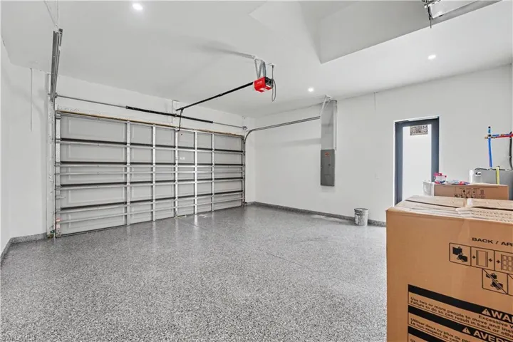 Spacious garage featuring a durable epoxy floor, white walls, recessed lighting, and an overhead garage door opener