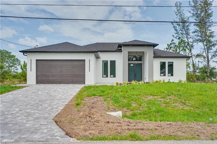 Modern stucco exterior with a dark shingle roof and a paver driveway