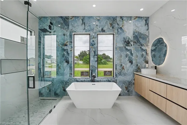 Modern bathroom featuring a freestanding soaking tub, a spacious walk-in shower with a glass enclosure, and a floating wood-finish vanity