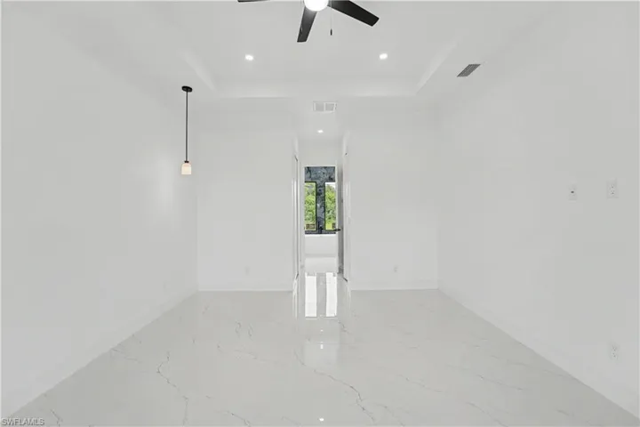 Spacious room featuring white walls and large format tile flooring