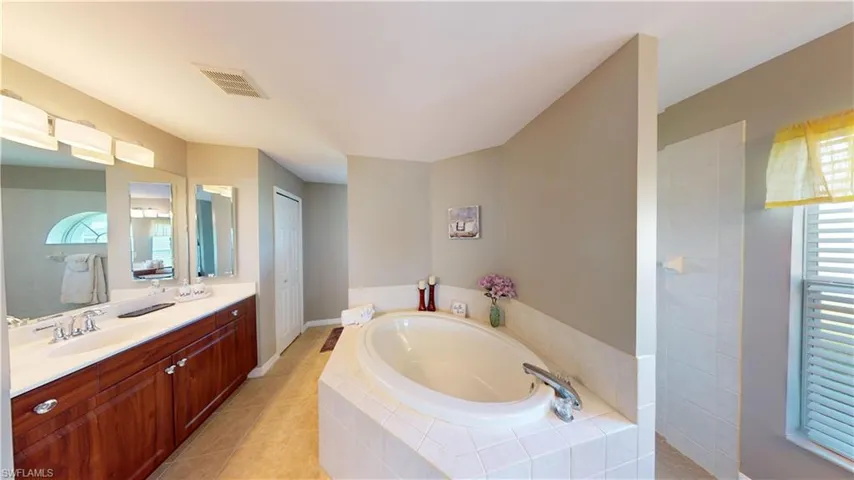 Primary bathroom suite with soaking tub, dual sinks and vanities, separate make-up vanity, walk through shower with dual shower heads and private toilet room.