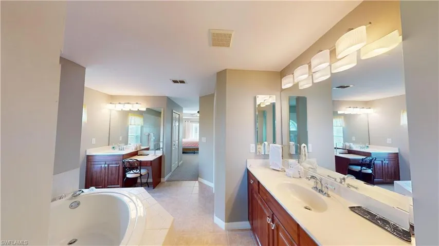 Bathroom with tile patterned flooring, tiled bath, and vanity