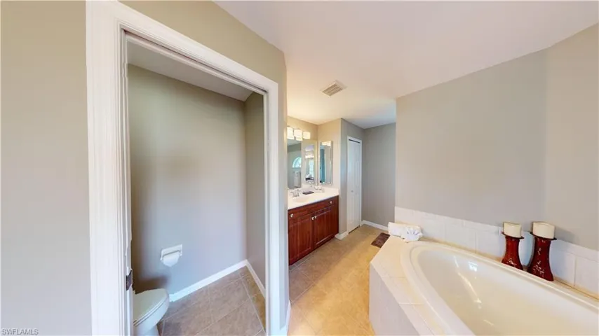 Primary bathroom suite with soaking tub, dual sinks and vanities, separate make-up vanity, walk through shower with dual shower heads and private toilet room.