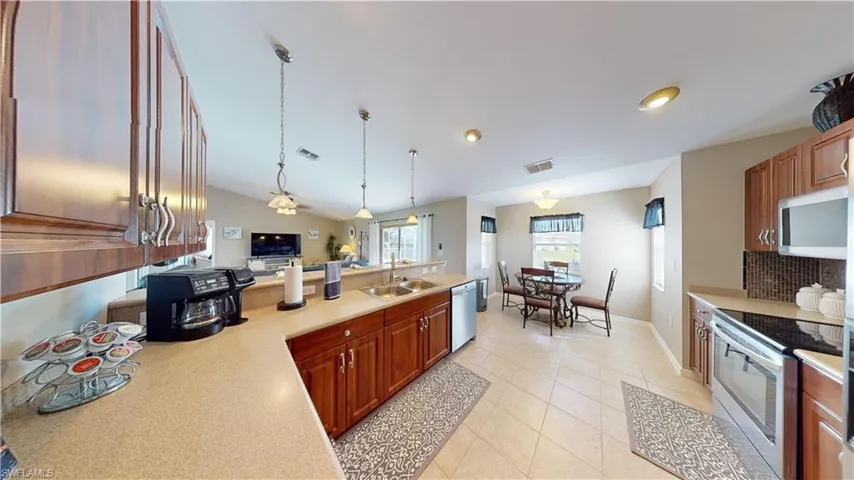 Kitchen with lofted ceiling, light tile patterned floors, decorative light fixtures, stainless steel appliances, and decorative backsplash