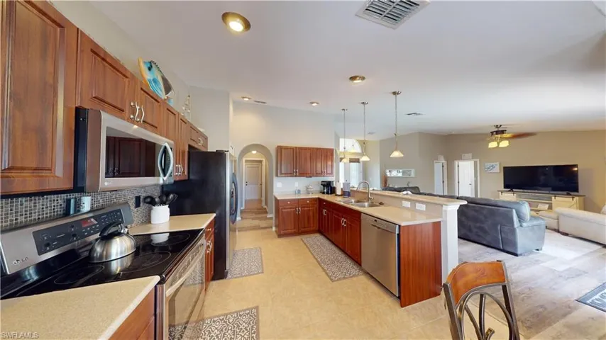 Kitchen with tasteful backsplash, sink, hanging light fixtures, appliances with stainless steel finishes, and ceiling fan