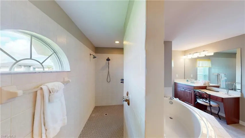 Primary bathroom suite with soaking tub, dual sinks and vanities, separate make-up vanity, walk through shower with dual shower heads and private toilet room.