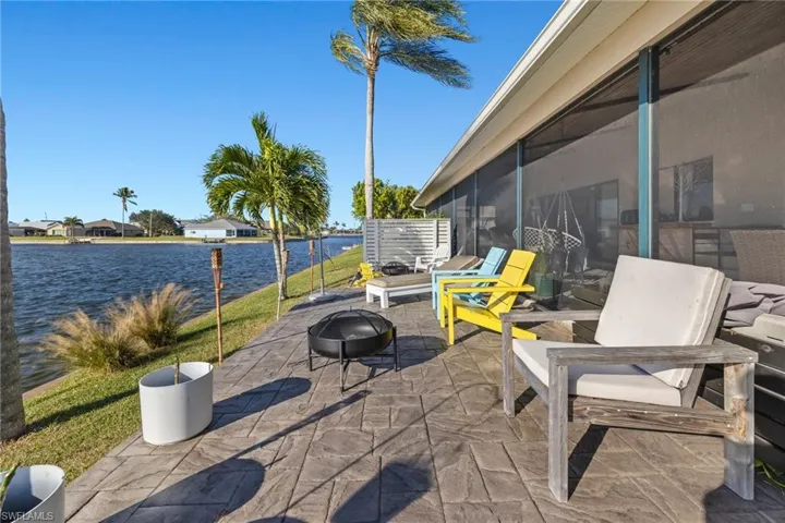 View of patio with a fire pit, a sunroom, and a water view