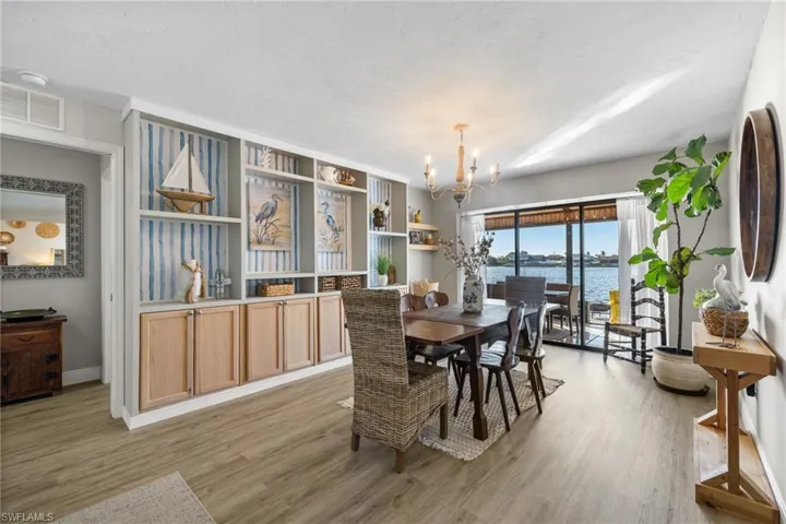 Dining room featuring a notable chandelier, a water view, and light wood-type flooring