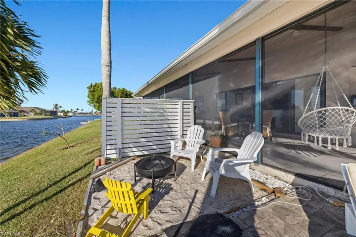 View of patio with a fire pit, a sunroom, and a water view